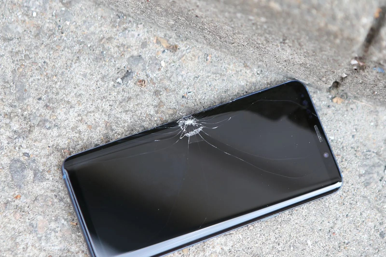 Smartphone à l’écran fendu, posé au sol